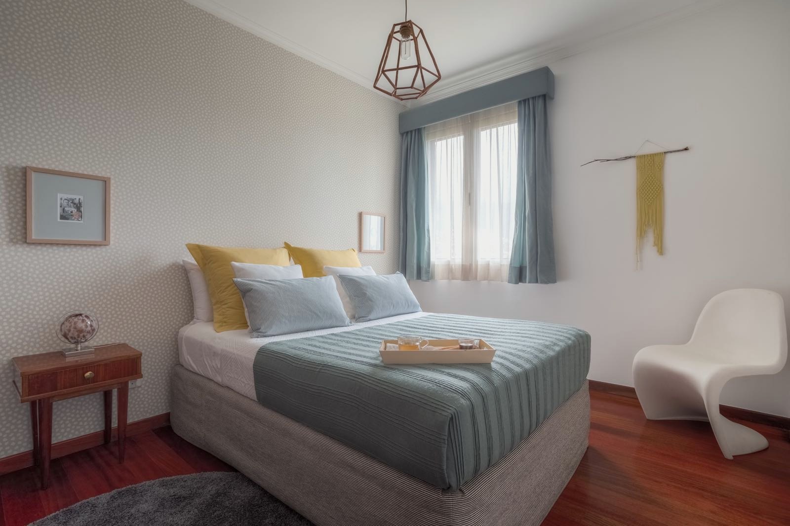 Santa Catarina Apartment — Bedroom with a grey striped bedspread, mustard cushions and a white chair