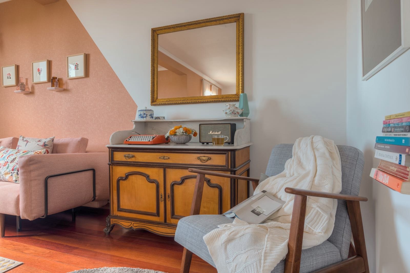 Santa Catarina Apartment — Timber sideboard with a gilded mirror, beside an armchair with a knitted throw