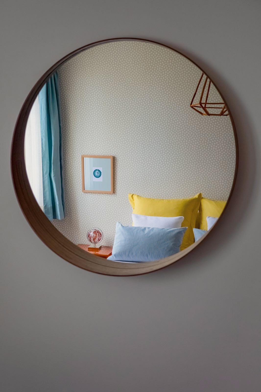 Santa Catarina Apartment — Round timber-framed mirror reflecting the bedroom