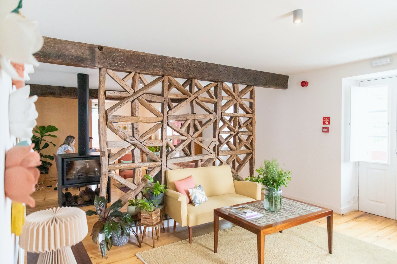 Socalco Nature Calheta — Living room with a carved timber lattice screen, a wood stove and a yellow sofa
