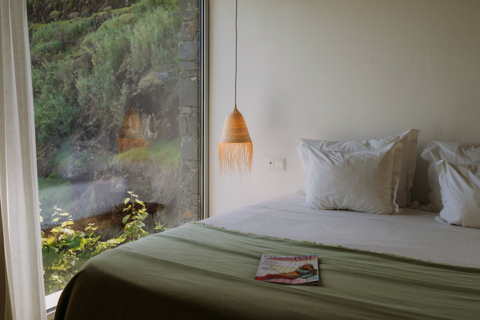 Socalco Nature Calheta — Bedroom with a green bedspread and a woven pendant, next to a window onto green terraces