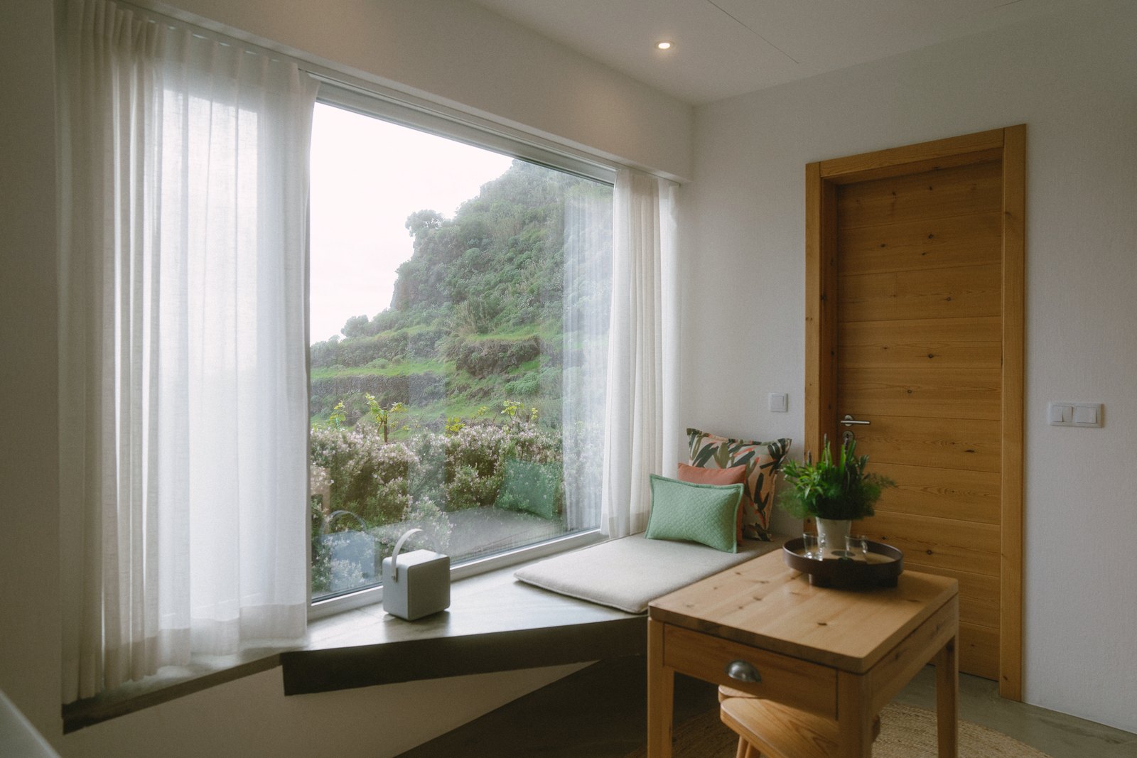Socalco Nature Calheta — Window seat with cushions and a small timber table, looking out to the hillside